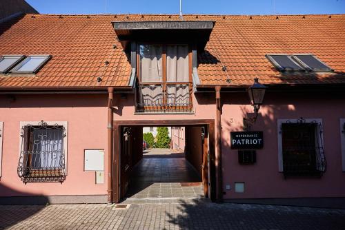 an alleyway leading to a pink building with a balcony at HOTEL Garni PATRIOT in Trnava