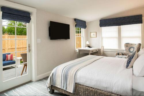 a bedroom with a bed and a television and a balcony at Edgar Hotel Martha's Vineyard, an Ascend Collection Hotel in Edgartown