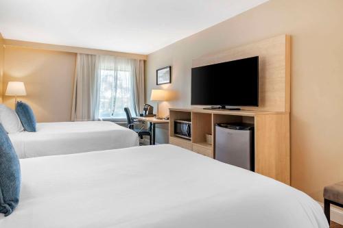 a hotel room with two beds and a flat screen tv at Casco Bay Hotel Portland Airport - Maine Mall, an Ascend Collection Hotel in South Portland
