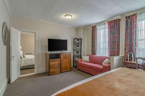 a living room with a red couch and a television at Hotel Bothwell Sedalia Central District, an Ascend Collection Hotel in Sedalia
