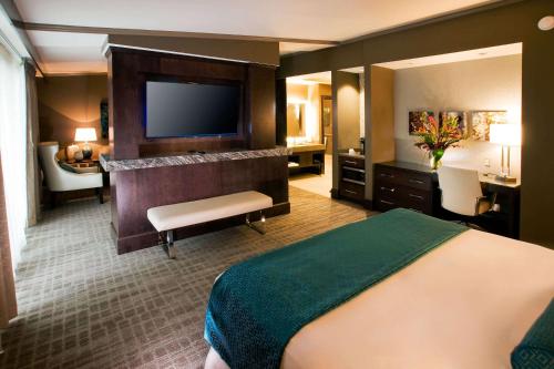 a hotel room with a bed and a flat screen tv at Oasis Hotel and Conv Center, an Ascend Collection Hotel in Springfield