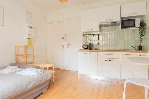 une cuisine avec des armoires blanches et un lit dans une chambre dans l'établissement Studio rénové à Nancy - Gare, à Nancy