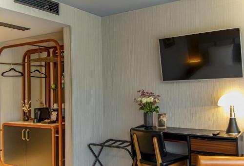 a room with a desk and a television on a wall at MUZE Hotel Dusseldorf - Handwritten Collection in Düsseldorf