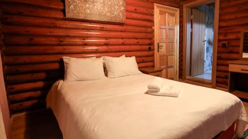 a bedroom with a white bed in a wooden wall at Sevgi Tepesi Bolu Panorama Otel in Bolu
