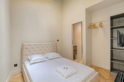 une chambre avec un grand lit blanc avec deux oreillers dans l'établissement T2 neuf proche Lyon, St-Didier-au-Mont-d'Or, à Saint-Didier-au-Mont-dʼOr