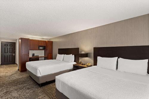 a hotel room with two beds and a kitchen at Wingate by Wyndham South Bend - Notre Dame in South Bend
