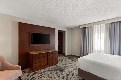 a hotel room with a bed and a flat screen tv at Wingate by Wyndham South Bend - Notre Dame in South Bend
