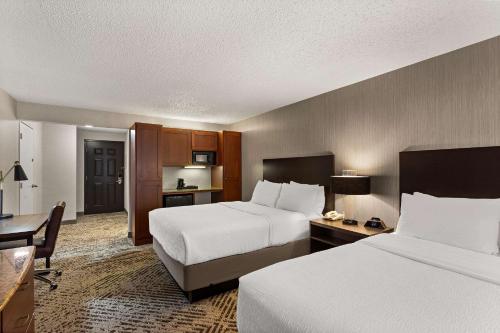 a hotel room with two beds and a desk at Wingate by Wyndham South Bend - Notre Dame in South Bend