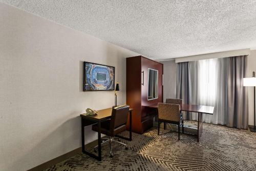 a hotel room with a desk and a table and chairs at Wingate by Wyndham South Bend - Notre Dame in South Bend