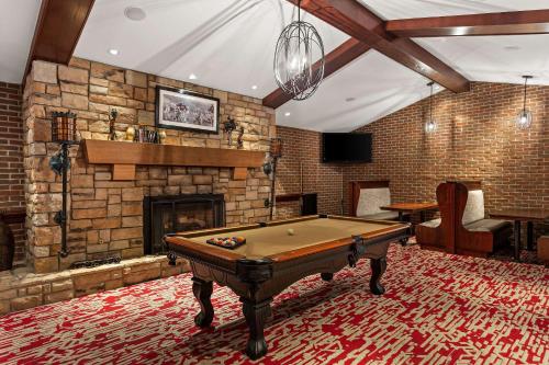 a pool table in a room with a brick fireplace at Wingate by Wyndham South Bend - Notre Dame in South Bend