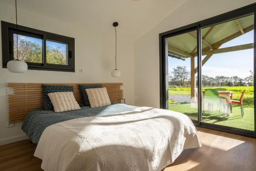 a bedroom with a bed and a large window at Kergueguen - Charmante maison avec jardin in Clohars-Carnoët