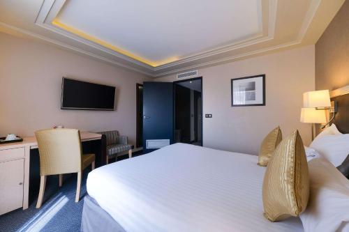 a hotel room with a bed and a desk and a television at Zenitude Hotel la Valadière, an Ascend Collection Hotel in Montpellier
