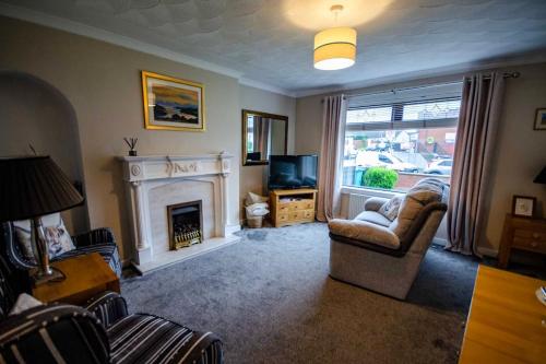 a living room with a fireplace and a chair and a television at Spacious 4-Bedroom House in Glenboig in Glenboig