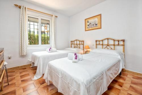 two beds in a room with white walls and wooden floors at F04 Bahia Playa - Apartment in Mijas Costa