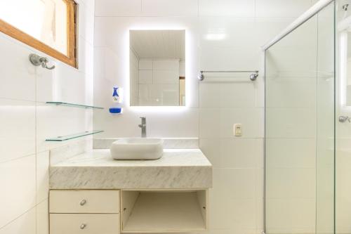 a white bathroom with a sink and a shower at Lindo Loft na Praia de Barra do Una à beira do Rio in São Sebastião