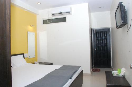 Habitación de hotel con cama y TV en Vitthal Inn, en Pandharpur