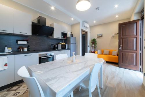 a kitchen and living room with a white table and chairs at Casa Rubbo - Appartamento 'Como' nelle Langhe in Alba