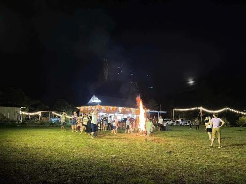 Un grupo de personas de pie alrededor de un fuego en un campo. en NaNa Farm, en Bak Kan