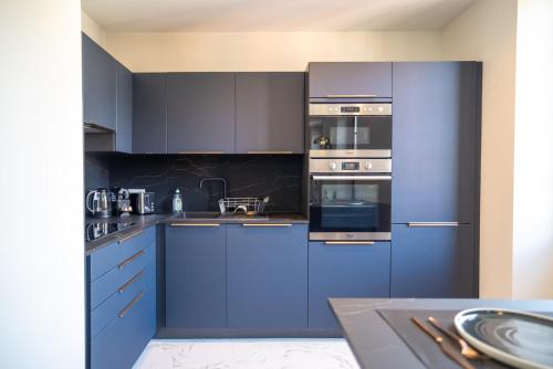 une cuisine bleue avec des appareils en acier inoxydable et des armoires bleues dans l'établissement GuestReady - Lovely Getaway, à Nice