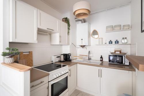 une cuisine blanche avec des armoires et des appareils blancs dans l'établissement Malouine - A 450m de la plage avec garage privatif, à Saint-Malo