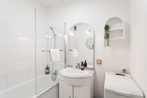 une salle de bain blanche avec un lavabo et une douche dans l'établissement Malouine - A 450m de la plage avec garage privatif, à Saint-Malo