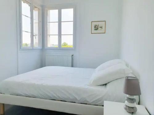 une chambre blanche avec un lit et deux fenêtres dans l'établissement Appartement très lumineux à deux pas de Paris, à Suresnes
