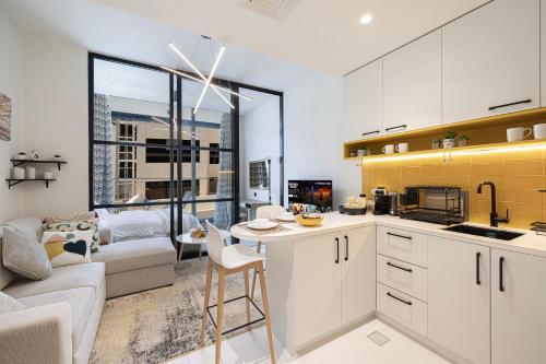 a kitchen with white cabinets and a living room at UrbanHomes - Cozy Spacious Exceptional Studio in Heart of Dubai at JVC in Dubai