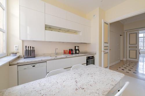 une cuisine avec des armoires blanches et un comptoir en marbre dans l'établissement Timeless Elegance in Paris, à Paris