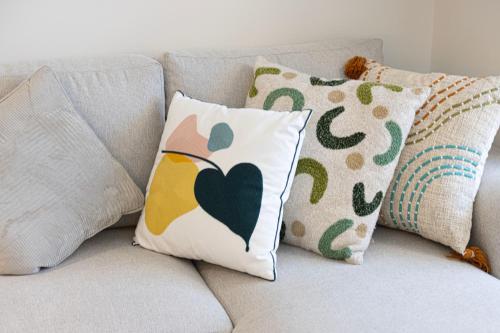 a couch with pillows and a bird pillow on it at UrbanHomes - Cozy Spacious Exceptional Studio in Heart of Dubai at JVC in Dubai