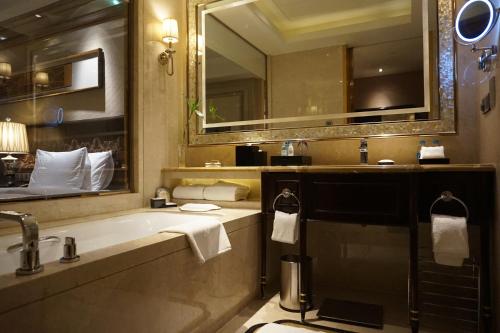 a bathroom with a tub and a sink and a mirror at Wanda Realm Harbin Hotel in Harbin