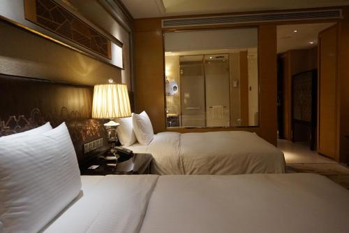 a hotel room with two beds and a lamp at Wanda Realm Harbin Hotel in Harbin