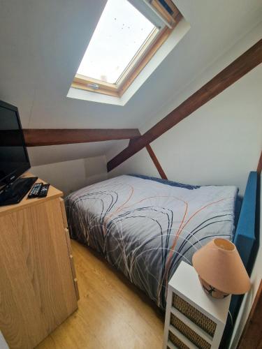 une chambre mansardée avec un lit et une fenêtre dans l'établissement Lumineuse maison ancienne dans le centre Cabourg, à Cabourg