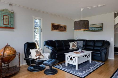 a living room with a black leather couch and chairs at Sauna cabin | Pets allowed | Engine heater in Lofsdalen