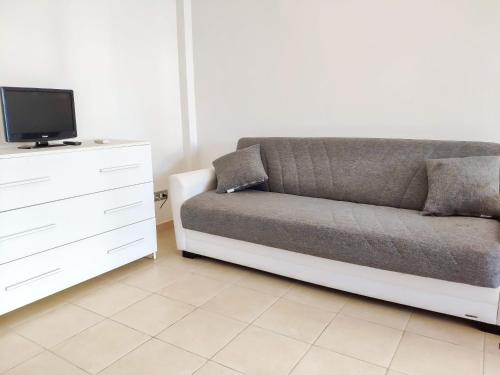 a couch sitting next to a dresser with a tv at Homiday - Holiday Rendez Vous in Pineto