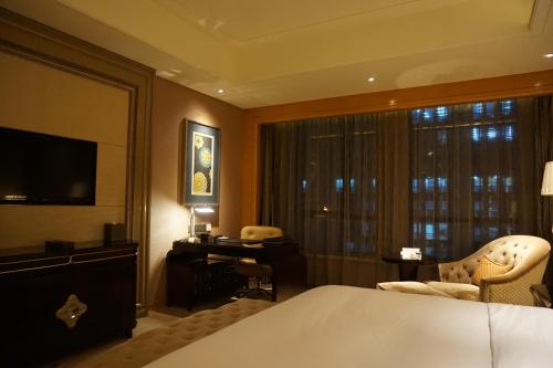 a hotel room with a bed and a desk and a television at Wanda Realm Harbin Hotel in Harbin