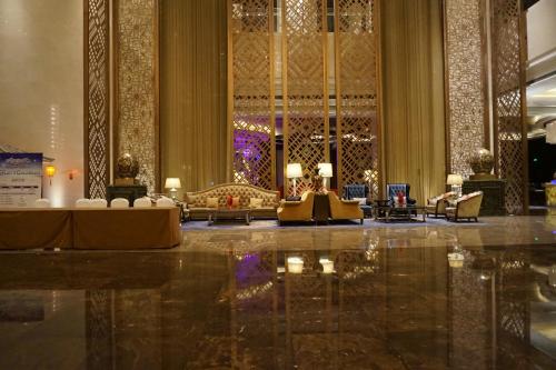 a lobby with tables and chairs in a building at Wanda Realm Harbin Hotel in Harbin