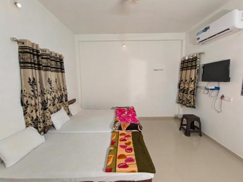 a room with a bed and a tv and curtains at Mamta Homestay in Garudeshwar