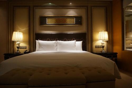 a bedroom with a large white bed with two lamps at Wanda Realm Harbin Hotel in Harbin