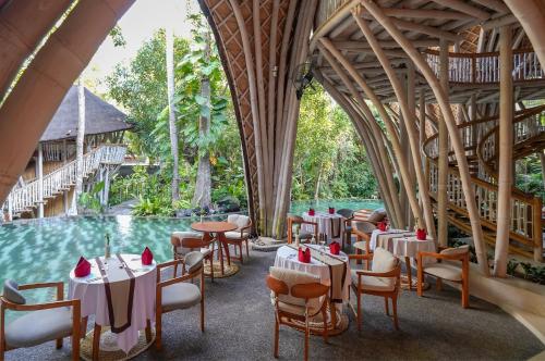 un ristorante con tavoli e sedie accanto a una piscina di Ulaman Eco Luxury Resort a Tabanan