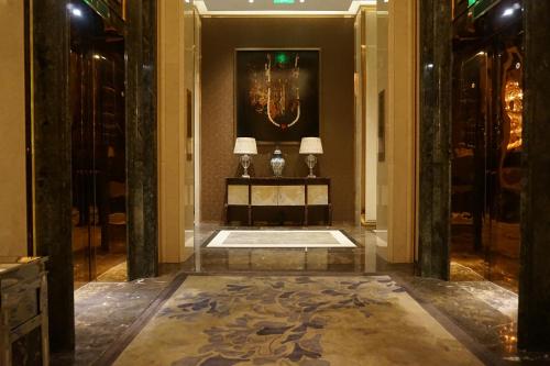 a hallway with two lamps and a table in a building at Wanda Realm Harbin Hotel in Harbin