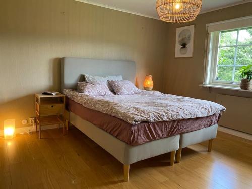 a bedroom with a bed with a night stand and a window at Cosy villa near forest and lake in Osby