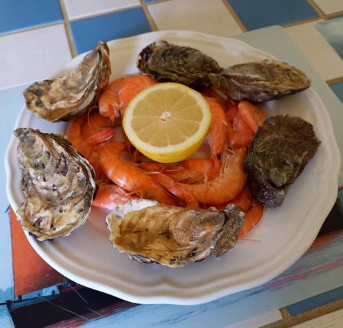une assiette de nourriture avec des fruits de mer et un citron dans l'établissement Gîte DA GOUSKET ROZ, à Trébeurden