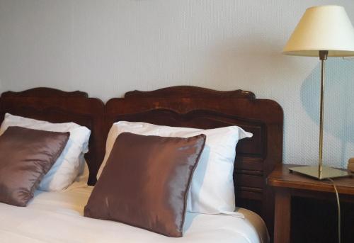 a bed with two pillows and a table with a lamp at Hotel Saint Etienne in Caen