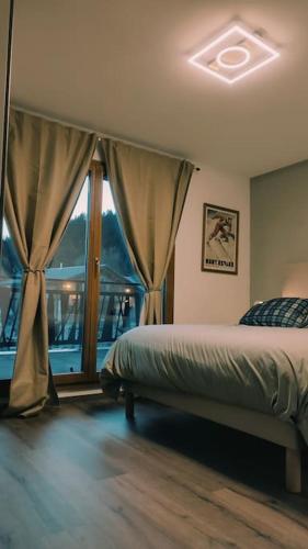 une chambre avec un lit et une grande fenêtre dans l'établissement La Feclaz - Duplex 90m2 au pied des pistes, à Les Déserts