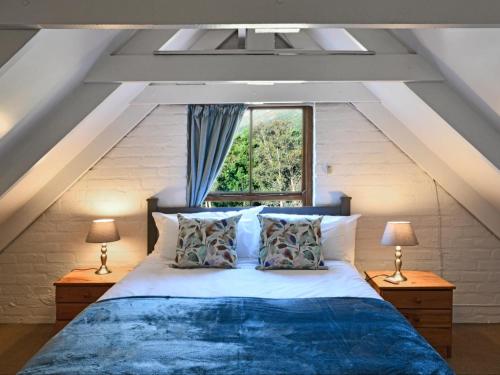 a bedroom with a bed with two lamps and a window at Stonehedge Cottages in Franschhoek