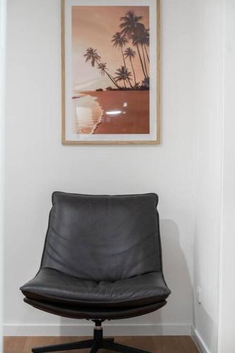 a black leather chair sitting under a picture on a wall at 2BR Home with Outdoor Deck with Beach Nearby M10 in Brisbane