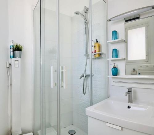 une salle de bain blanche avec une douche et un lavabo dans l'établissement charmant T2 50m plage de Pontaillac, à Royan
