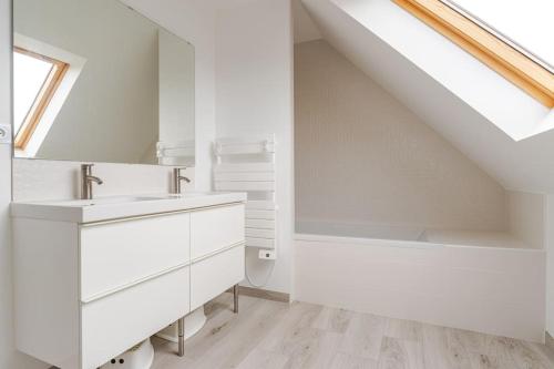 La salle de bains blanche est pourvue d'un lavabo et d'une lucarne. dans l'établissement Grande maison neuve classée 4 étoiles à 300m de la mer, à Plobannalec-Lesconil