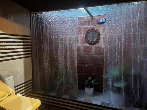 a bathroom with a shower curtain and a clock at Zyamadhari in Mananthavady