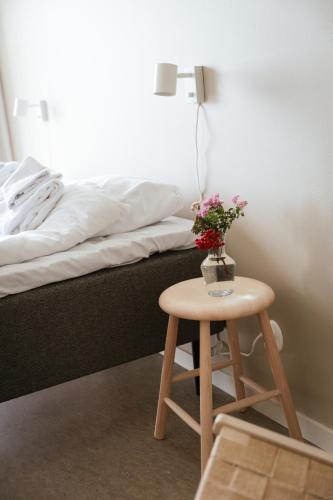 a small table with flowers on it next to a bed at STF Undersvik Gårdshotell & Vandrarhem in Vallsta
